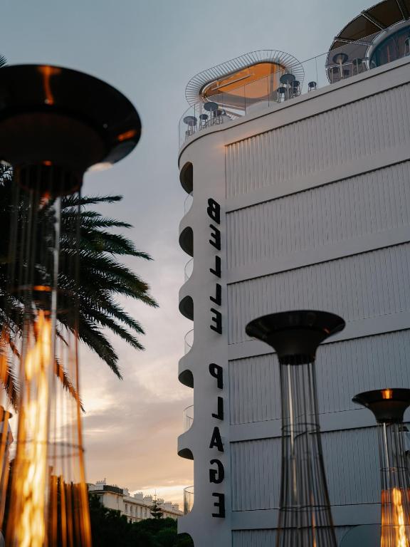 a hotel in front of a building with a palm tree at Hôtel & Spa Belle Plage in Cannes