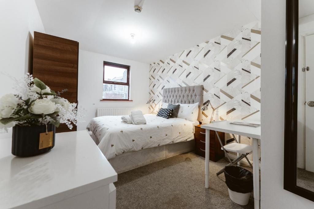 a white bedroom with a bed and a desk at Whitechapel en-suite beds to stay in London