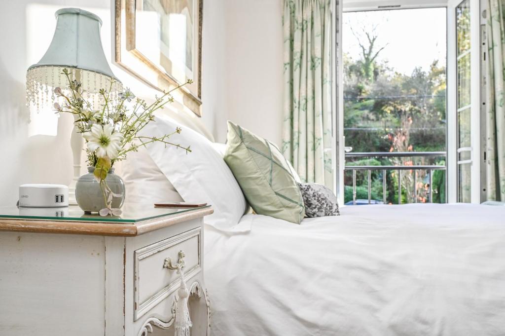 una camera da letto con un letto e un tavolo con un vaso di fiori di Briardene Cottage - A Superb Bijou Retreat with Jacuzzi near an Excellent Village Pub a Yelverton