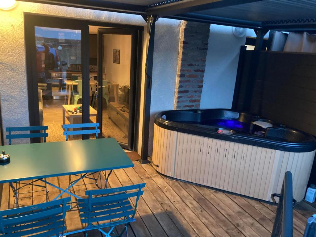 a hot tub on a deck with a table and chairs at Les spas de la Chartreuse in Tarbes