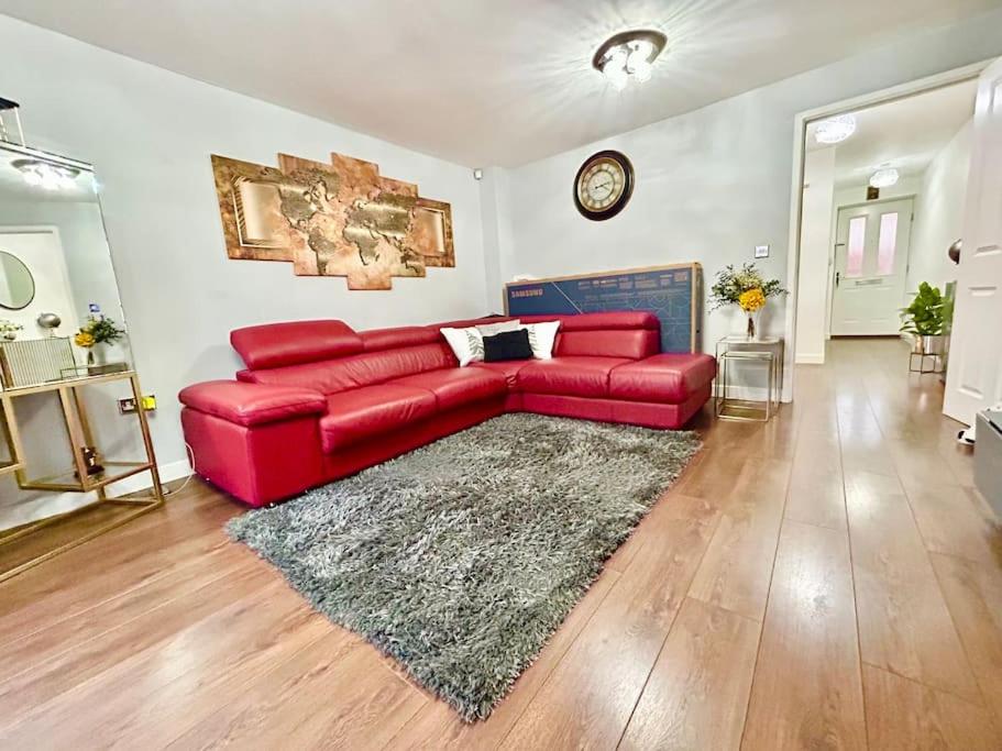 a red leather couch in a living room with a rug at Sensational 3-Bed Home Near Bluewater in Kent