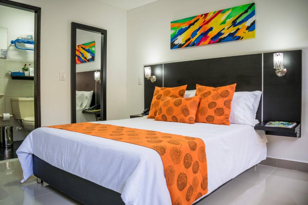 1 dormitorio con 1 cama grande con almohadas de color naranja en Hotel Montes De La Castellana en Armenia