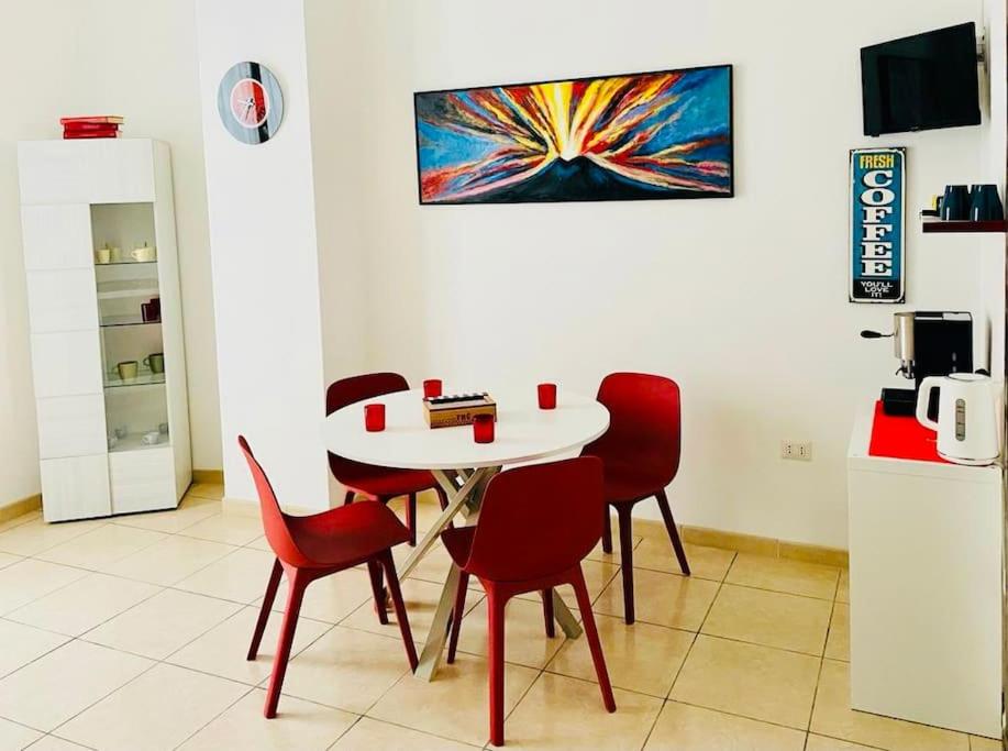 ein Esszimmer mit einem Tisch und roten Stühlen in der Unterkunft Napoli Forcella House al centro di Napoli in Neapel
