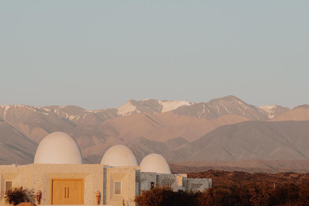 a building with three large white domes in front of mountains at Chozos Resort in Agrelo