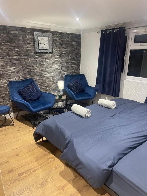 a bedroom with two blue chairs and a bed at Spacious loft converted bedroom with toilet only, Separate guest shower on ground floor plus free parking in Hanworth