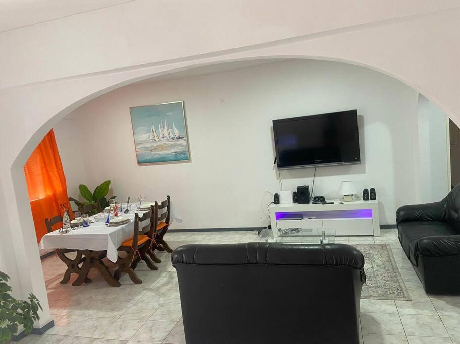 een woonkamer met een tafel en een flatscreen-tv bij Lovely Apartment In Mindelo City Center in Mindelo