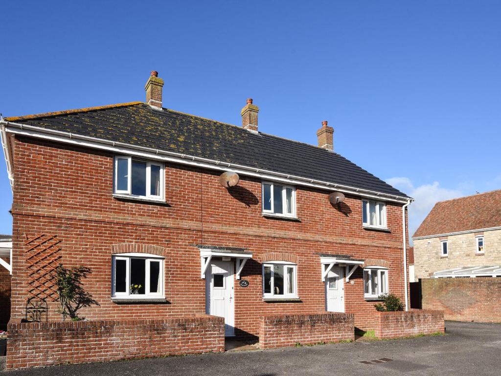 een rood bakstenen huis met witte deuren en ramen bij Mead Cottage in Bridport