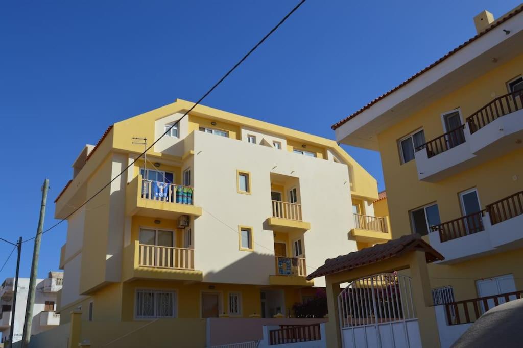 un edificio amarillo con balcones en un lateral en Tres Caravelas Studio Flats, en Santa Maria