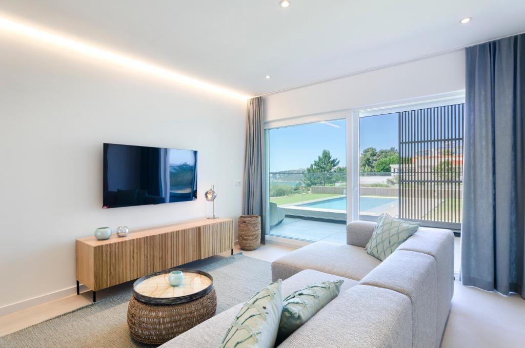 een woonkamer met een bank en een flatscreen-tv bij Mar a Vista - Condominium with Pool, Gym and Sea Views in Nazaré