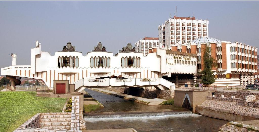 ein weißes Gebäude mit einer Brücke über einen Fluss in der Unterkunft Hotel Vrbak ND in Novi Pazar