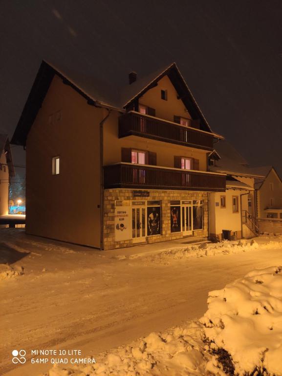 een groot gebouw in de sneeuw 's nachts bij Guesthouse Kusić in Kupres