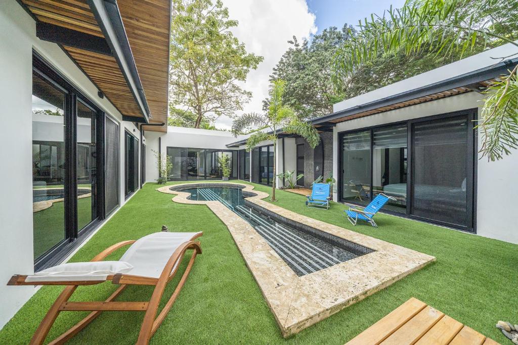 a backyard with a swimming pool and two chairs at Playa Potrero - NEW modern house, pool in guitar shape - Casa Guitarra in Potrero