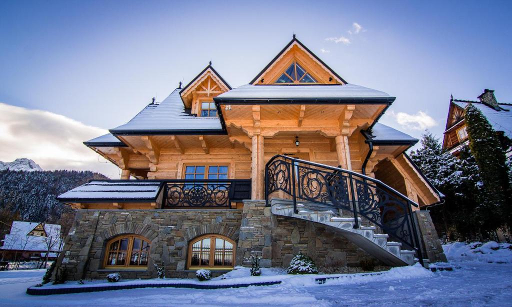 une maison en rondins avec un escalier dans la neige dans l'établissement Myśliwski Domek pod Giewontem, à Zakopane
