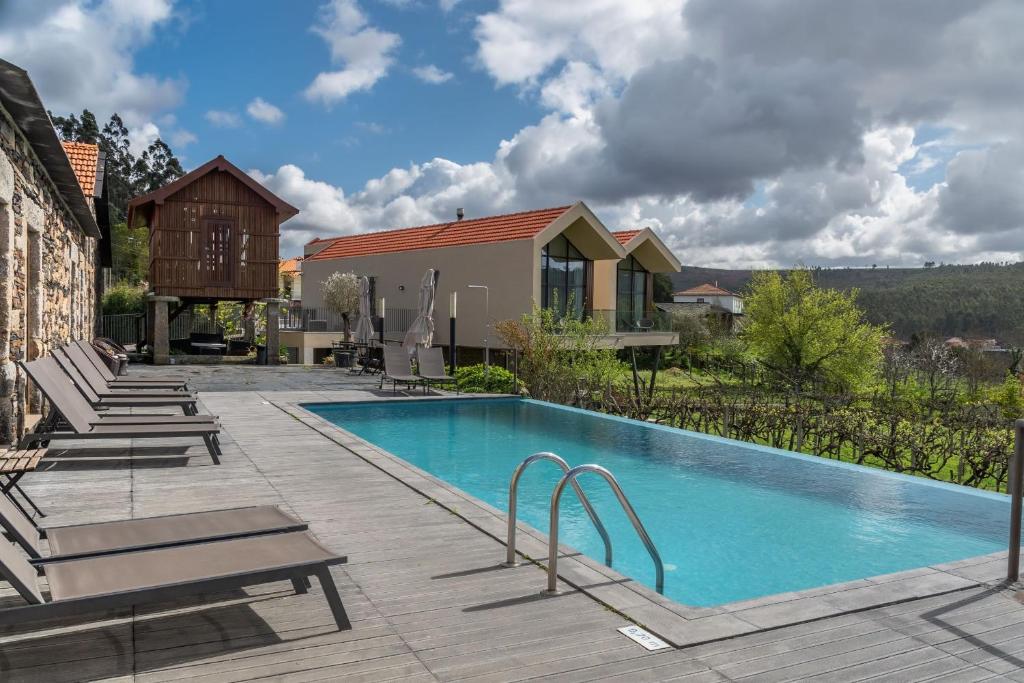 a swimming pool with chairs and a house at Casa Valxisto in Penafiel