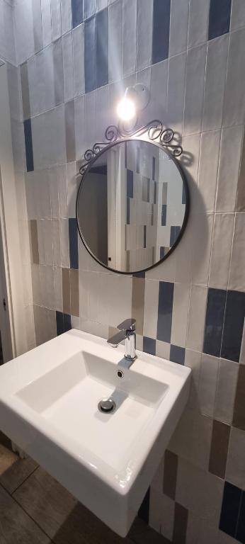 La salle de bains est pourvue d'un lavabo blanc et d'un miroir. dans l'établissement Farolfi Apartments Galliera Rooms & Apartments, à Bologne