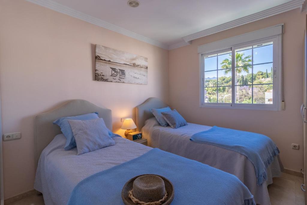 een kamer met 2 bedden met blauwe lakens en een raam bij Ático familiar con terraza y bonitas vistas al mar en Marbella - Rio Real 282G in Marbella