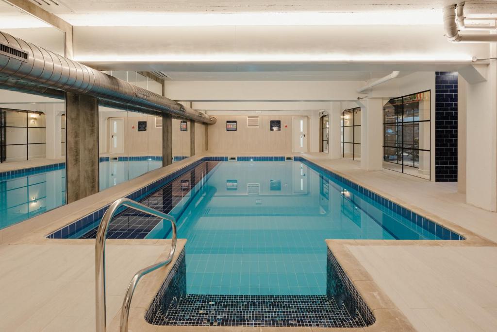 a large swimming pool with blue water in a building at Leicester Luxury Apartments - T45 in Leicester
