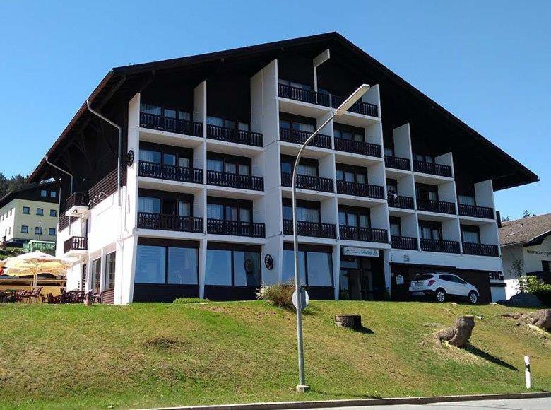 un gran edificio de apartamentos blanco con balcones y una señal de stop en Apartmány Almberg, en Philippsreut