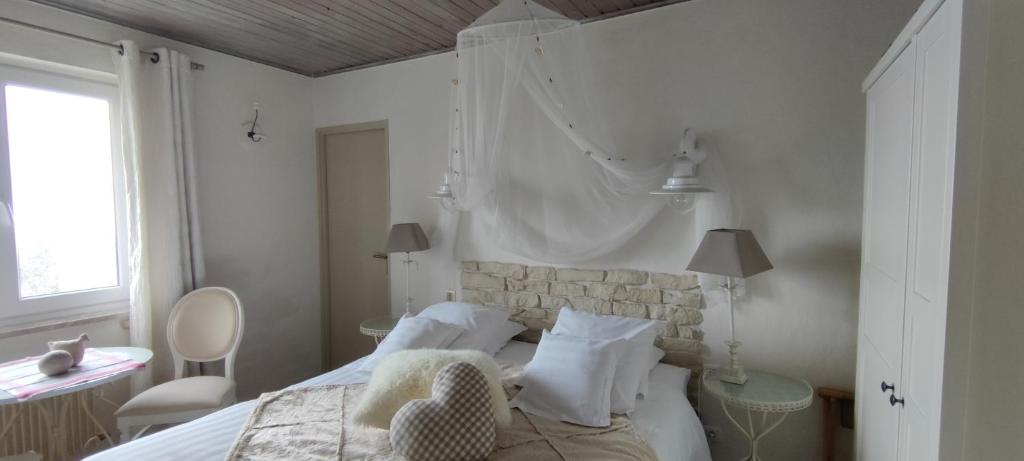 a white bedroom with a bed and a chair at Les 4 Saisons in Kruth