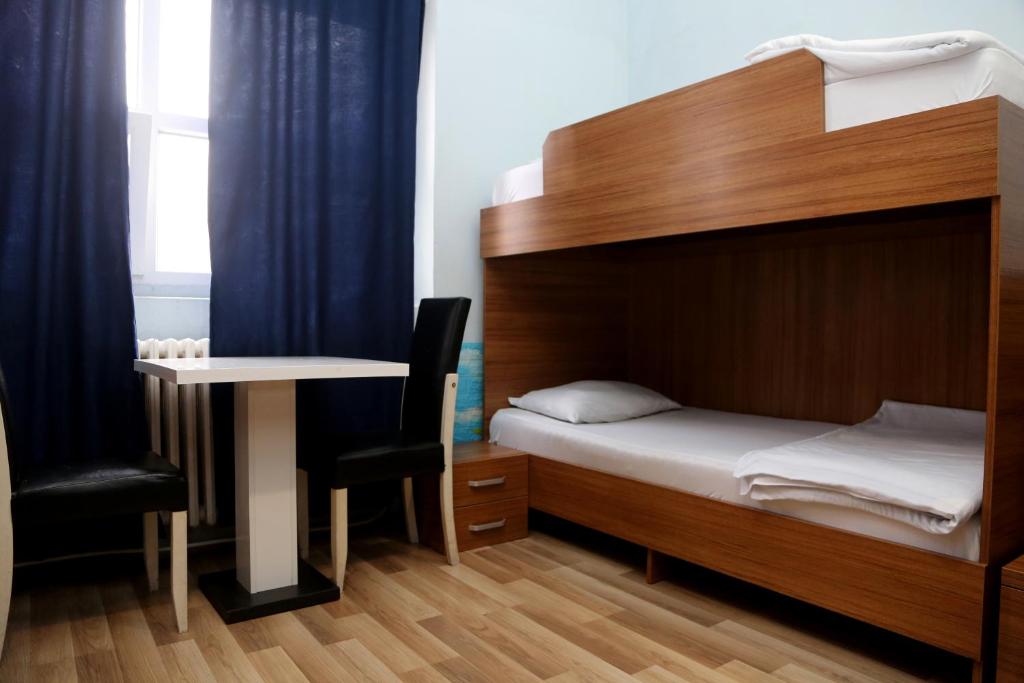 a bedroom with a bed and a desk and a table at Moon Hostel in Prishtinë