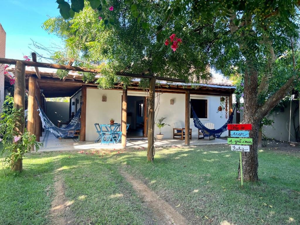 ein Haus mit einem Baum und einem Schild im Hof in der Unterkunft Bangalô de Charme na Praia do Patacho - Rota Ecológica dos Milagres in Pôrto de Pedras