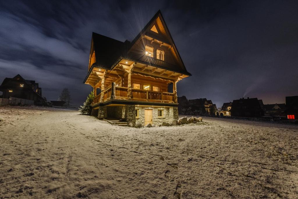 una cabaña de madera en la nieve por la noche en Domek Na Przełęczy wood house & mountain view, en Murzasichle