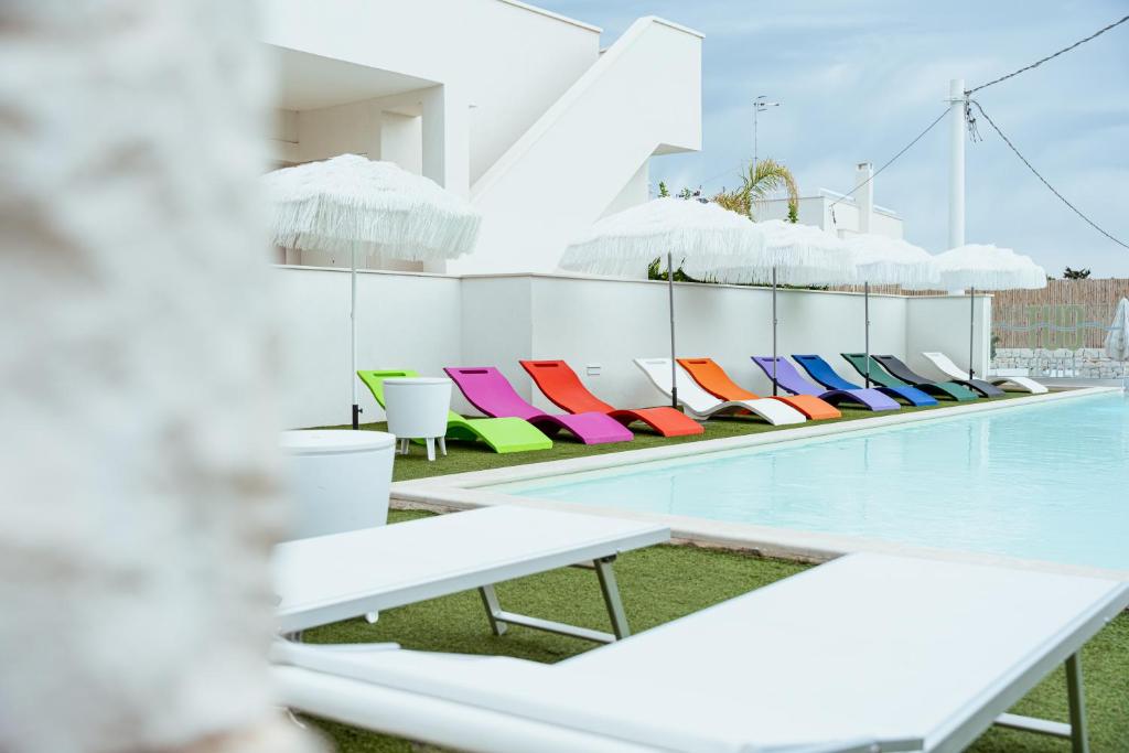 a row of colorful chairs next to a swimming pool at Tuo Hotel in Polignano a Mare