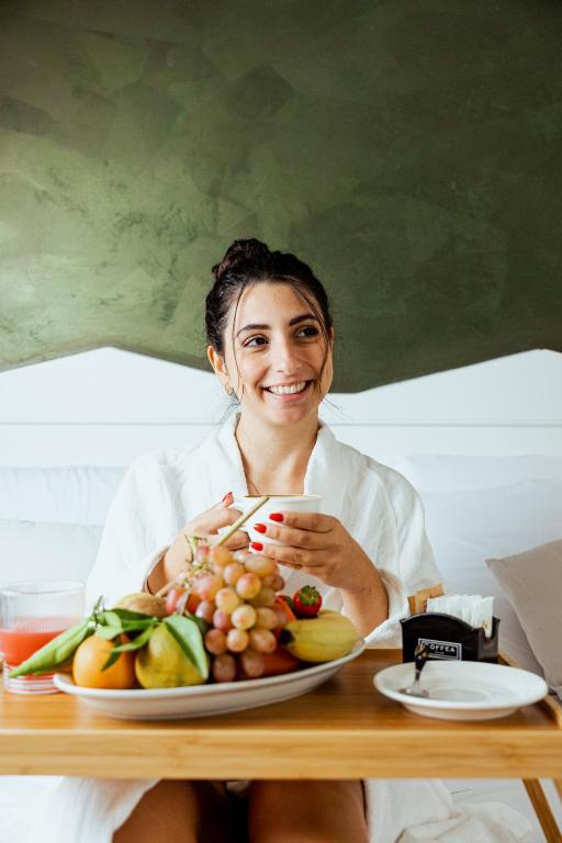 a woman sitting at a table with a plate of fruit at Tuo Hotel in Polignano a Mare