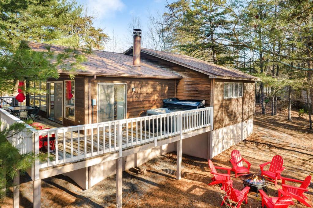 une maison avec une terrasse dotée de chaises rouges et d'un grill dans l'établissement Cabin w Hot Tub, Indoor Pool, Gym Access, & Grill, à Hedgesville