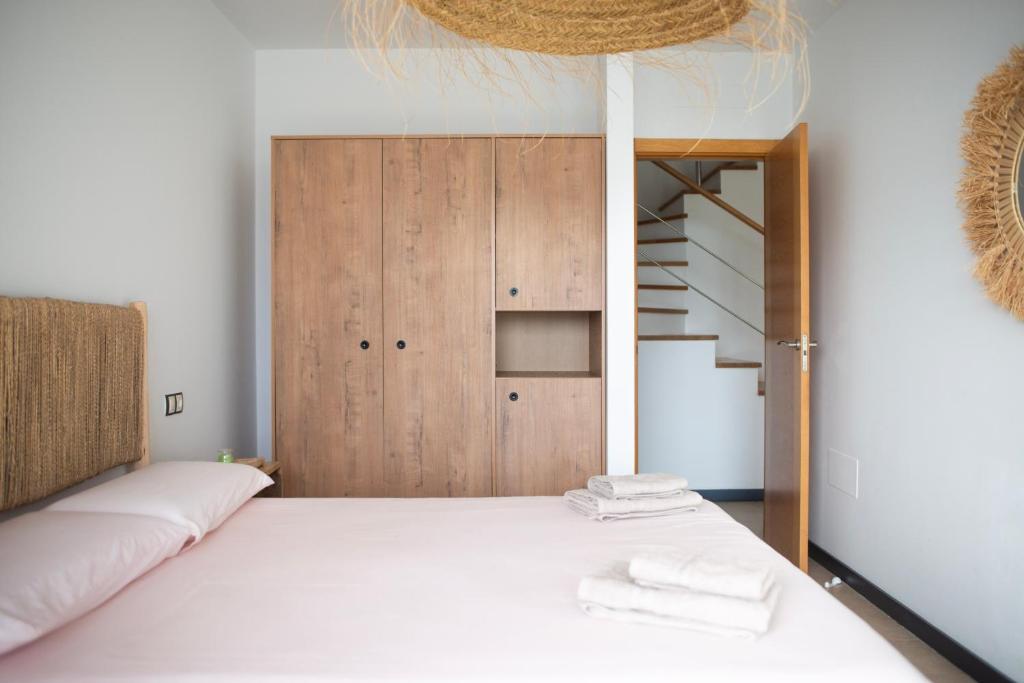 a bedroom with a bed with a wooden cabinet and a staircase at Ocean View Penthouse El Cotillo in Cotillo