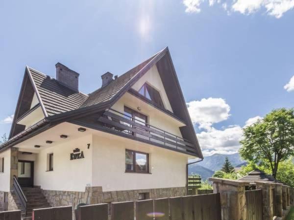 une maison blanche avec un toit noir et une clôture dans l'établissement Willa Ewka, à Kościelisko
