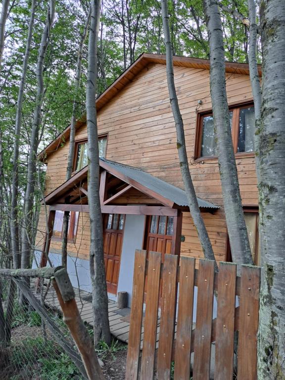 a log cabin in the woods with a wooden fence at La Casita del Bosque in Ushuaia