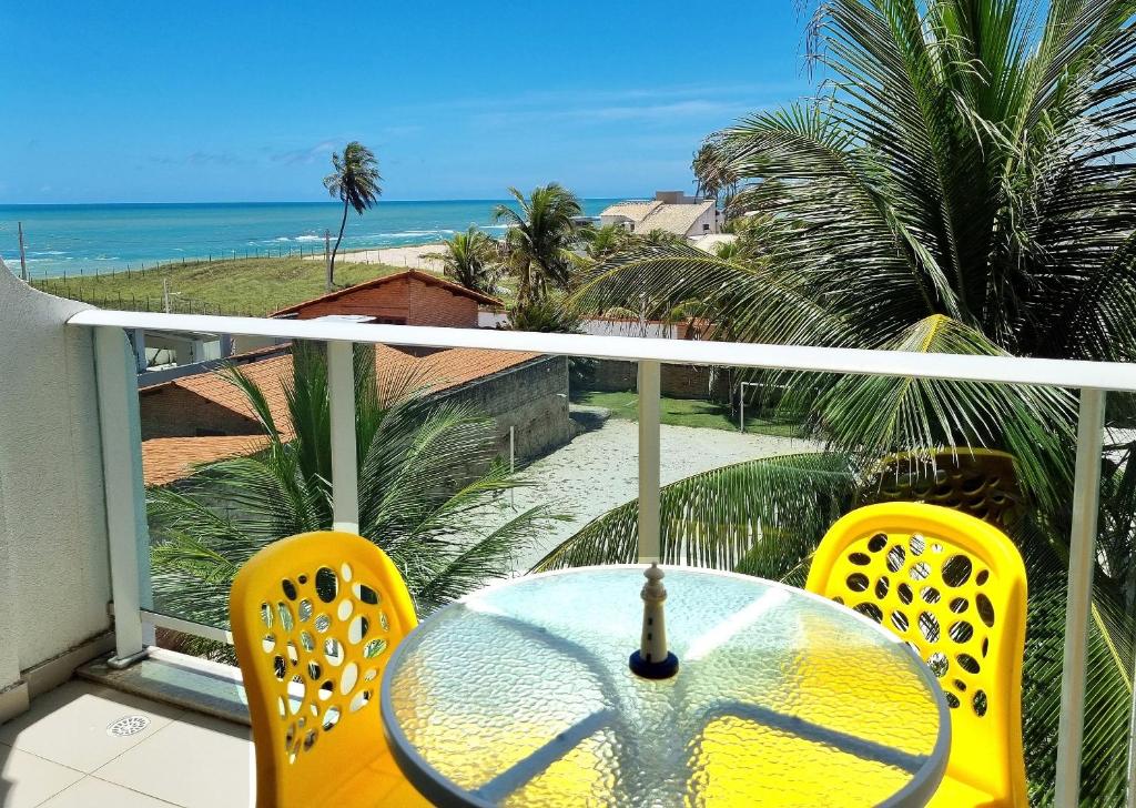 ein Tisch und zwei Stühle auf einem Balkon mit Blick auf das Meer in der Unterkunft Areias do Mar Aconchegante e Tranquilo com Varanda in Barra de São Miguel