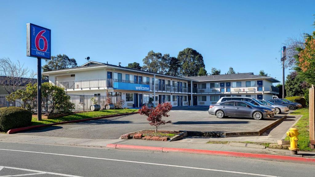 Motel 6-Arcata, CA Cal Poly Humboldt في أركاتا: مبنى فيه سيارات متوقفة في موقف للسيارات