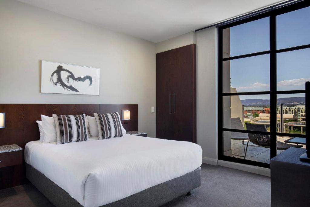 um quarto com uma cama grande e uma janela grande em Mantra Hindmarsh Square em Adelaide