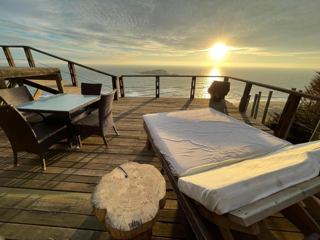 a wooden deck with a bed and a table and the sunset at Mirada al Mar in Matanzas