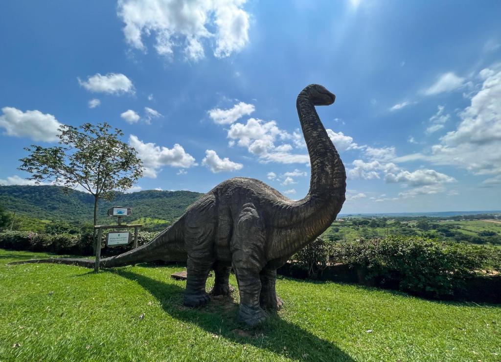 a statue of a dinosaur in a field at Pousada Vale do Dinossauro in São Pedro