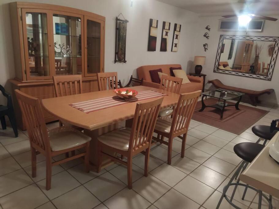uma sala de estar com uma mesa de madeira e cadeiras em Departamento amplio y amueblado en Marina Diamante em Acapulco