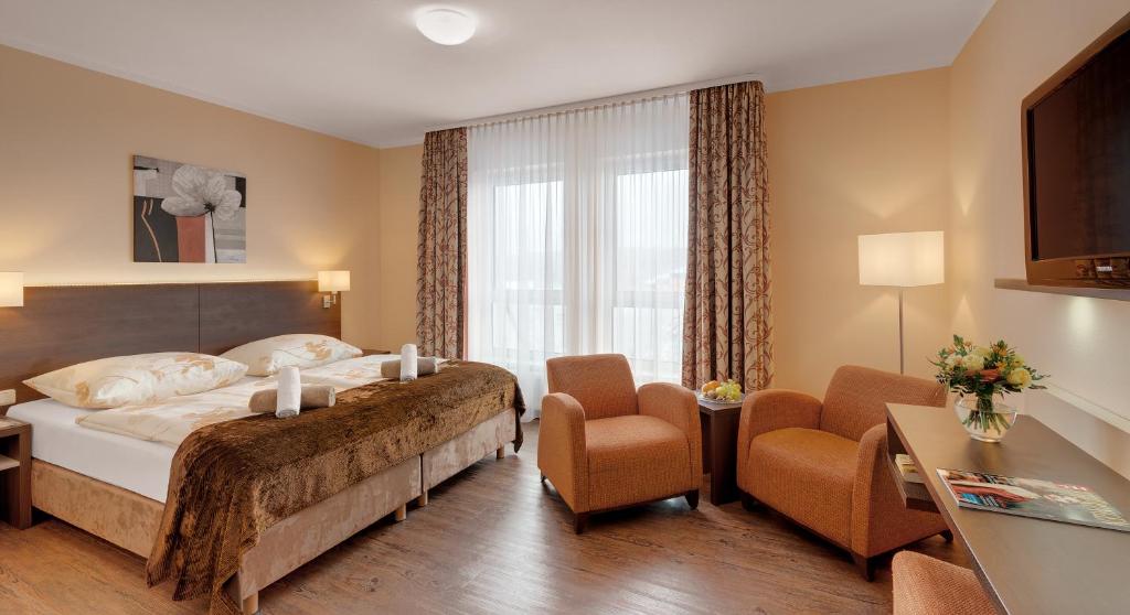 a hotel room with a bed and two chairs at Schlossberghotel Oberhof in Oberhof