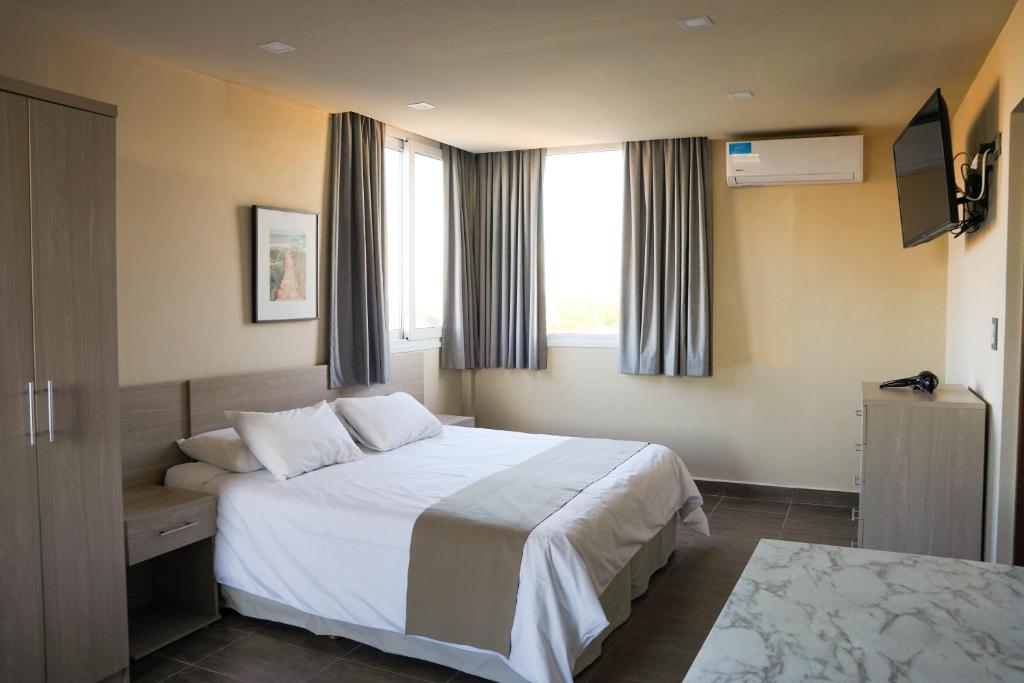 Una habitación de hotel con una cama y dos ventanas. en Solana - Apart Hotel & Club de Tenis, en Santa Clara del Mar