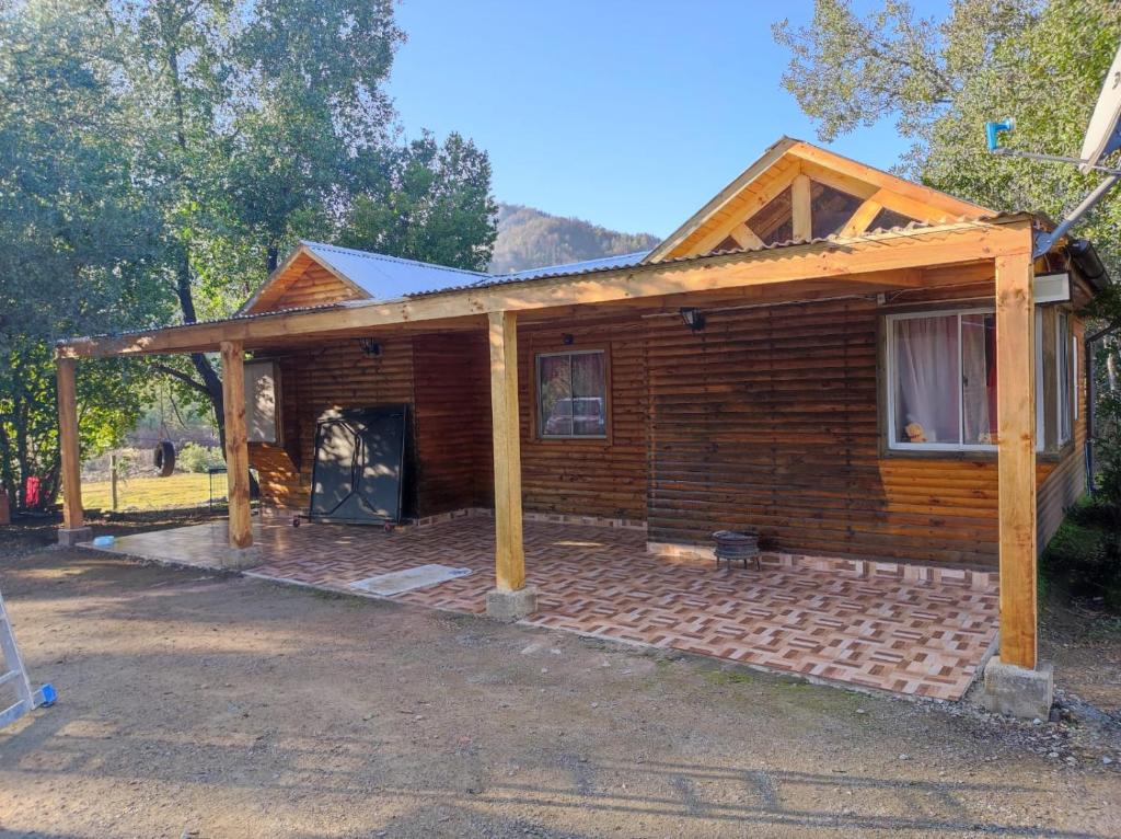 a log cabin with a porch on a brick patio at Cabaña en linares camino el embalse ancoa in Linares