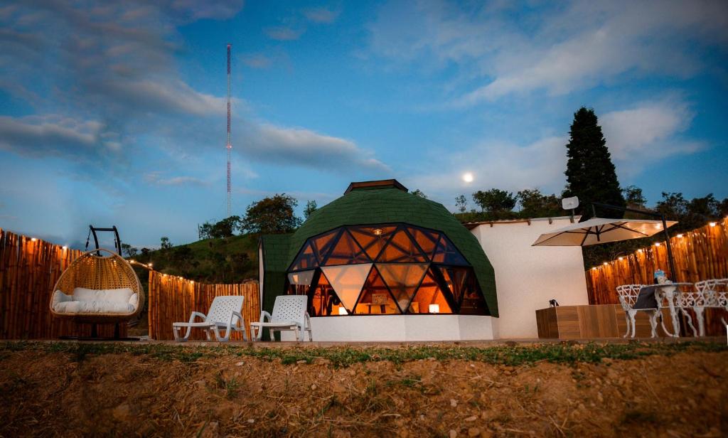 um gazebo com um telhado verde e algumas cadeiras e mesas em Glamping Monteverde San gil em San Gil