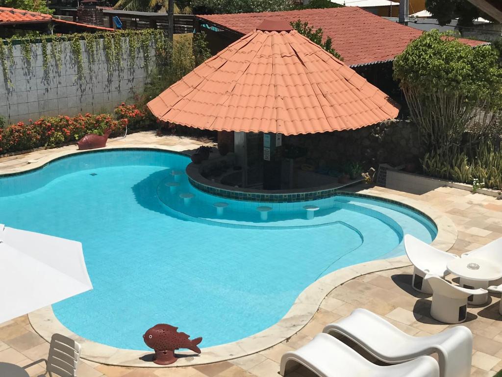 a swimming pool with a large umbrella and chairs at Suites Bouganville ( casa 2) in Porto De Galinhas