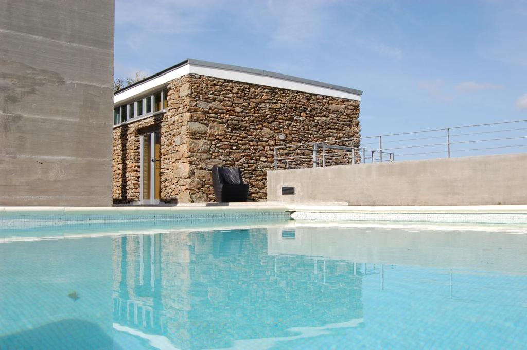 a building with a swimming pool in front of a building at Quinta dos Castanheiros - Turismo Rural in Negreda