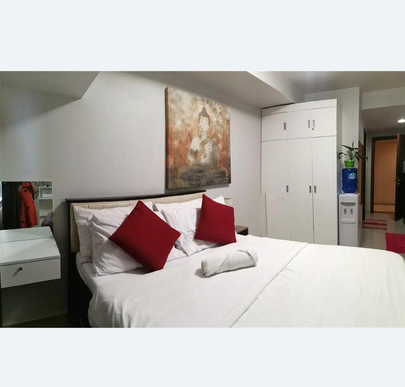 a bedroom with a white bed with two red pillows at Ghabian Property in Cebu City