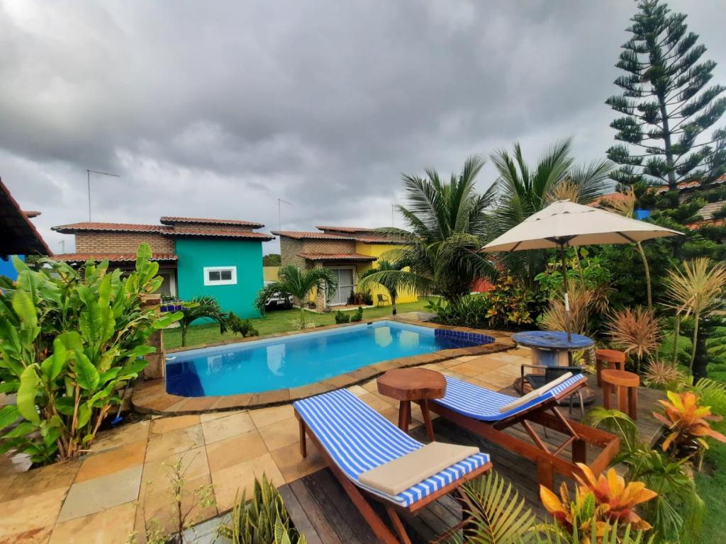 a backyard with a pool and chairs and a house at Villa da Praia in Pipa