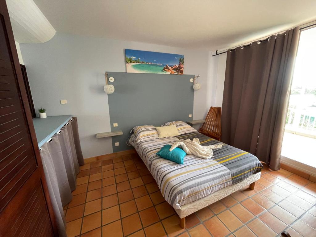 a small bedroom with a bed with a head board at CLANES LOCATION Acerola in La Trinité