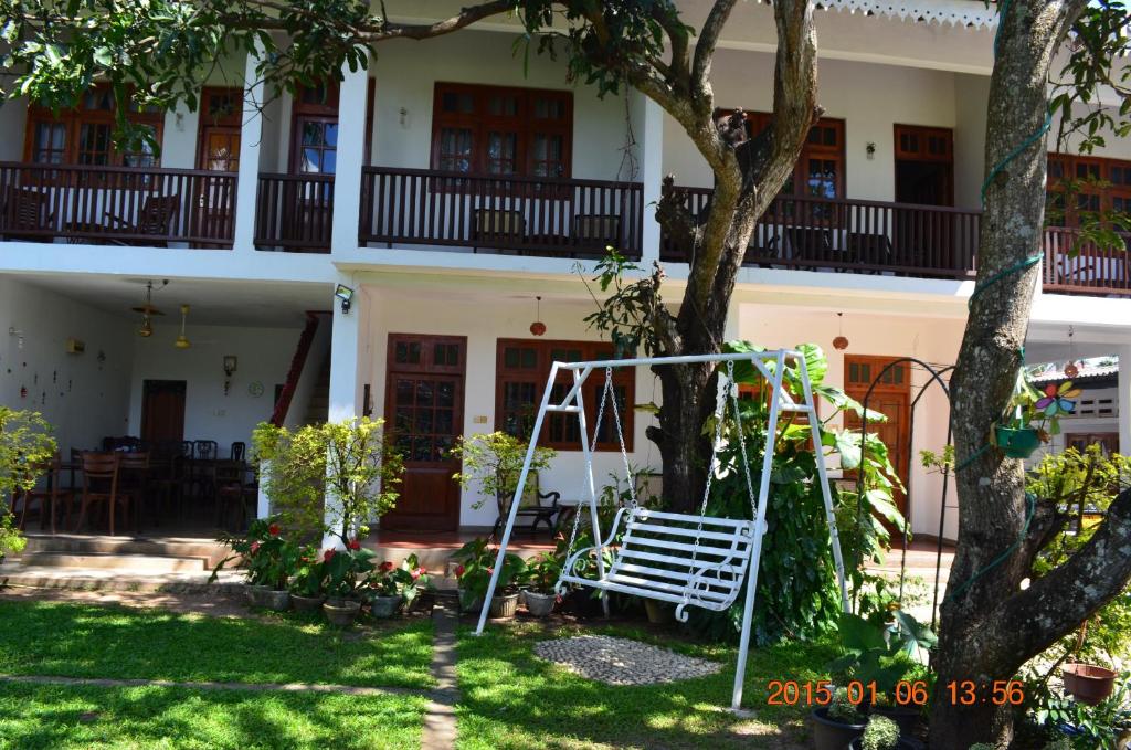 a white house with a tree and a swing at Little Paradise Tourist Guest House and Holiday Home in Anuradhapura