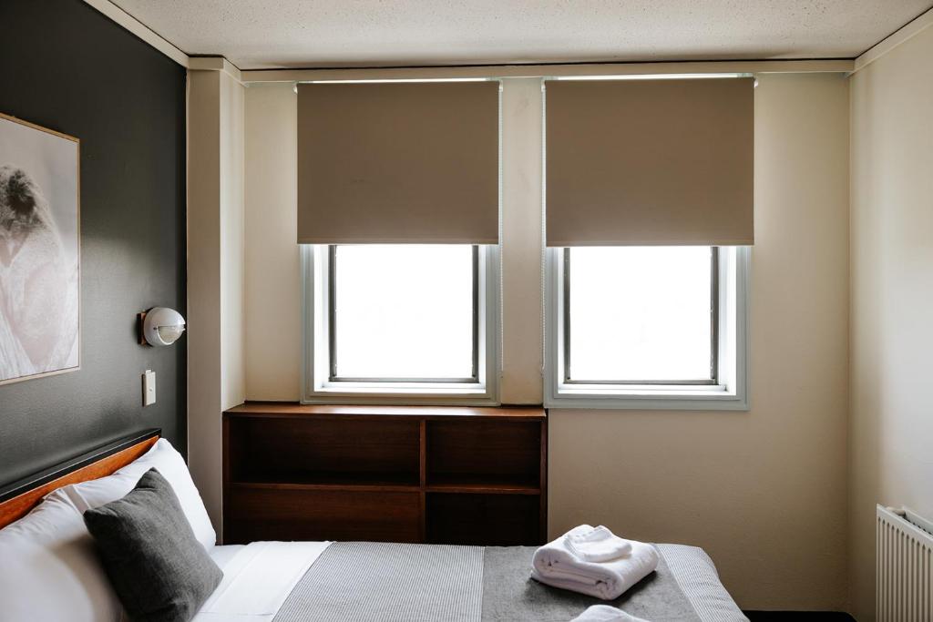 a bedroom with two windows and a bed with towels on it at Canberra Accommodation Centre in Canberra