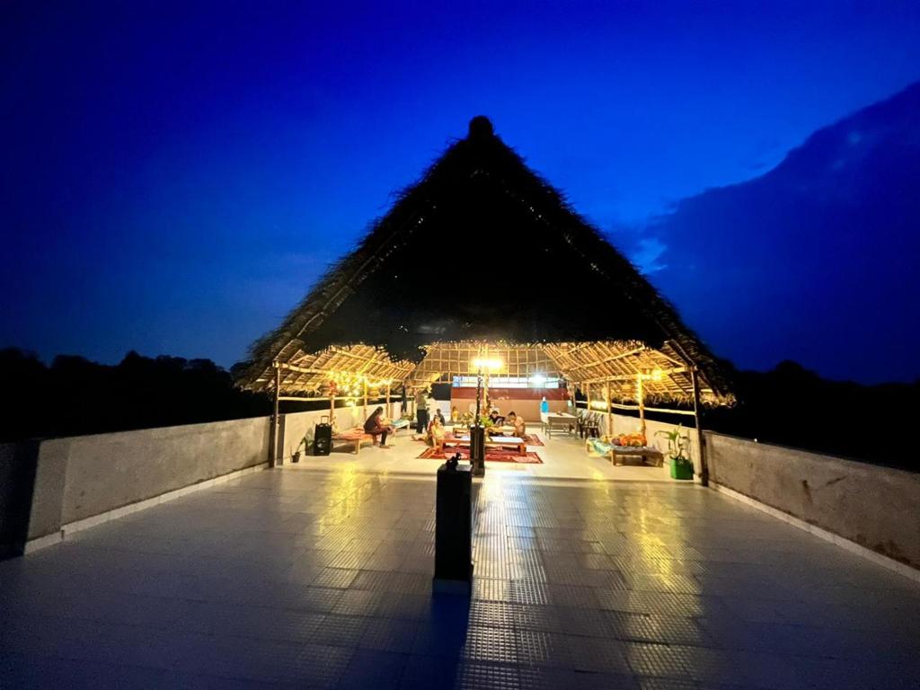 um edifício em pirâmide com um pátio iluminado à noite em WoodPacker Hostel Auroville Pondicherry em Auroville